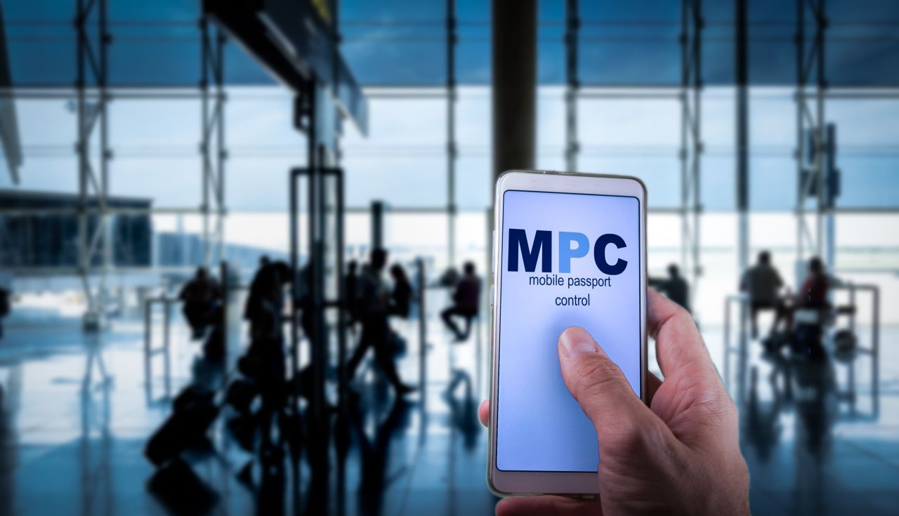 Traveler holding phone with Mobile Passport Control app in airport terminal